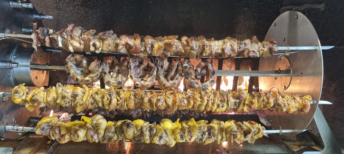 Spiedo di carne mista cotto lentamente alla brace sul girarrosto